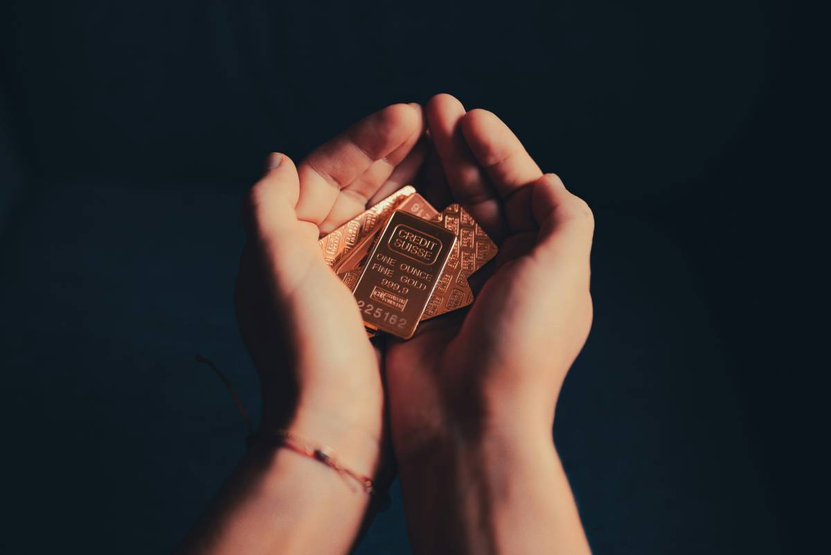 Close-up of scrap gold items like broken chains and earrings with text overlay: investing in gold and precious metals